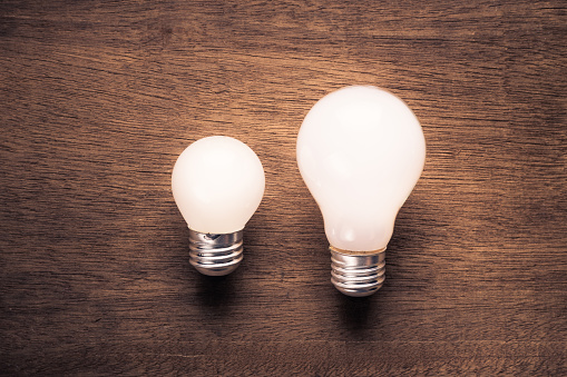 Small and big light bulb, small and medium sized business, coaching, training, or other comparison concept