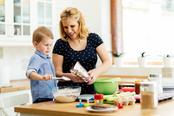 istock Smart cute child helping mother in kitchen preparing cookies 662031386