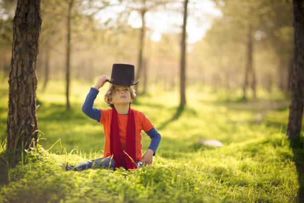 A young boy is playing funny at the park in a sunny beautiful day. The park is glowing from the early sun and it is all green due to the season. It can can be spring or summer.