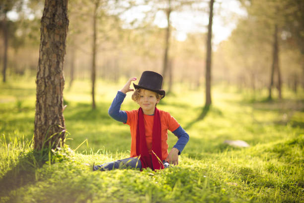A young boy is playing funny at the park in a sunny beautiful day. The park is glowing from the early sun and it is all green due to the season. It can can be spring or summer.
