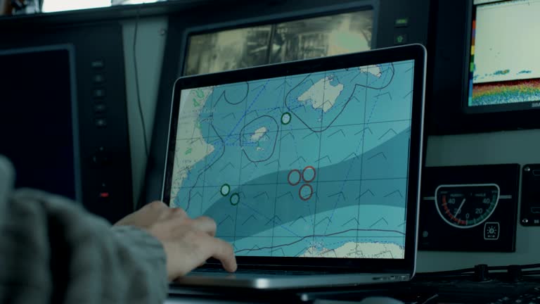 Captain of Commercial Fishing Ship Surrounded by Monitors and Screens Working with Sea Maps in his Cabin.