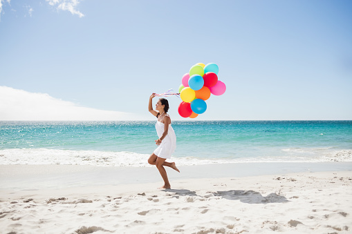 Beautiful woman holding balloon on the beach