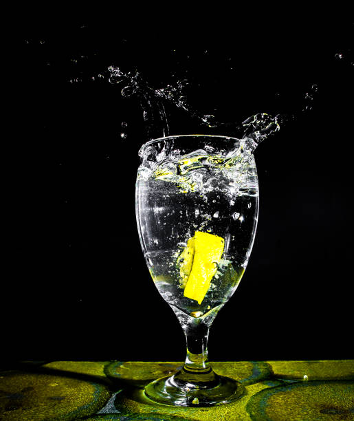A lime splashing into a glass of water stock photo