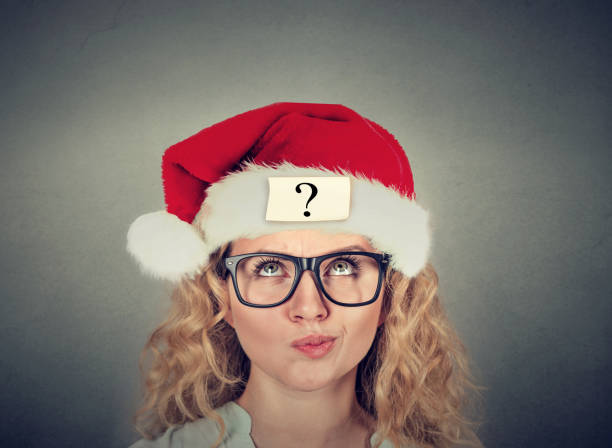 istock Thinking young woman in santa claus hat with question mark 662224646