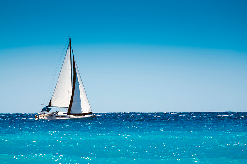 White boat sailing in the open blue sea in Greece