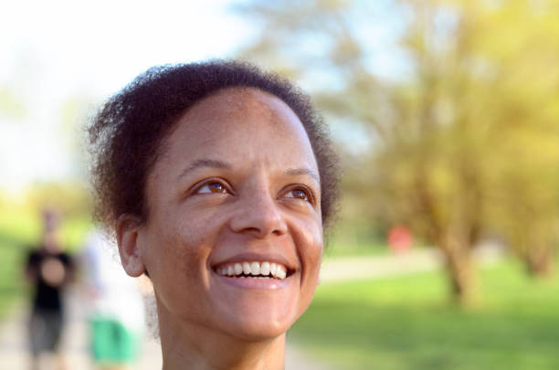 Side View of a Young african woman smiling while she is looking up to the sky