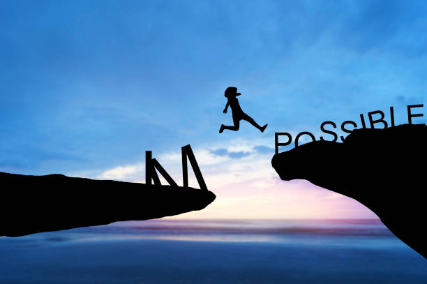 istock silhouette people jumping over the rock frome word impossible to possible 662423278