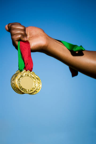 Athlete hand showing his gold medals in stadium