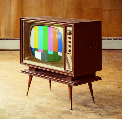 Vintage television with test pattern amidst a rundown home interior.