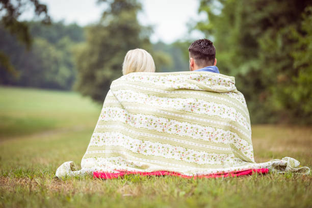 Happy couple sitting under blanket in the countryside