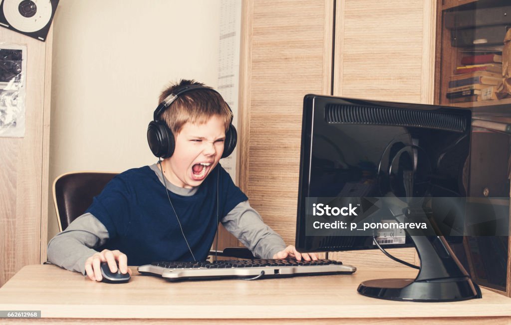 Gaming, entertainment, technology, let's play concept. Angry screaming pre teen Gaming, entertainment, technology, let's play concept. Angry screaming pre teen boy  in headset with pc computer playing game at home Child Stock Photo