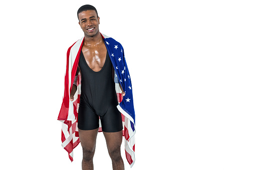 Athlete posing with american flag wrapped around his body on white background
