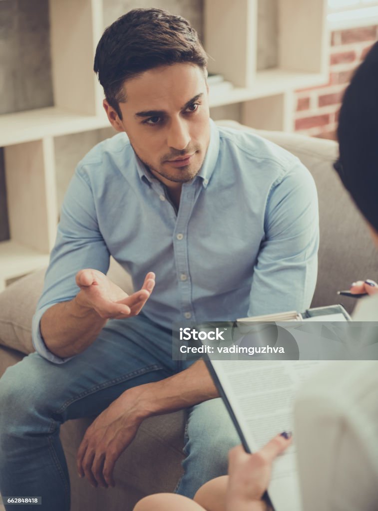 Guy at the psychologist Handsome young man is talking about his problems while sitting on the couch at the psychologist Psychotherapy Stock Photo