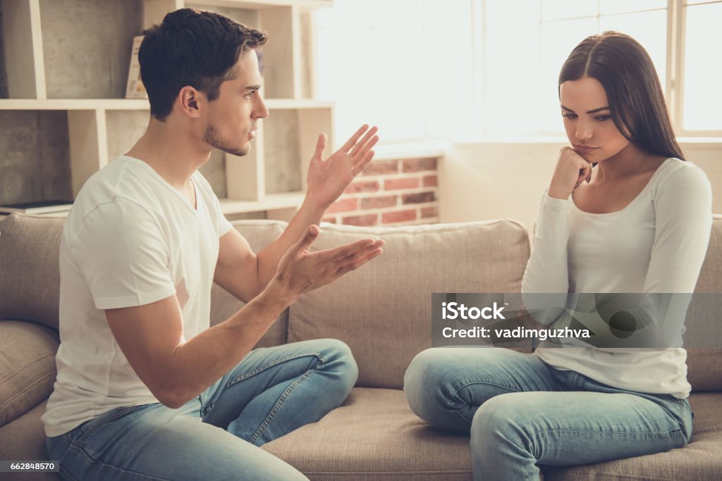 Couple at home Beautiful young couple is having a quarrel while sitting on sofa at home Couple - Relationship Stock Photo