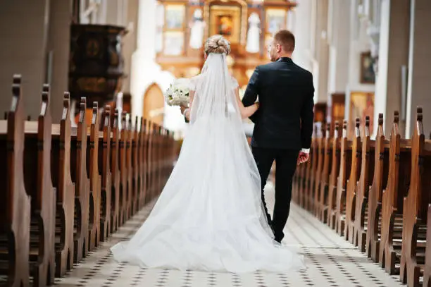 Photo of Photosession of stylish wedding couple on catholic church.