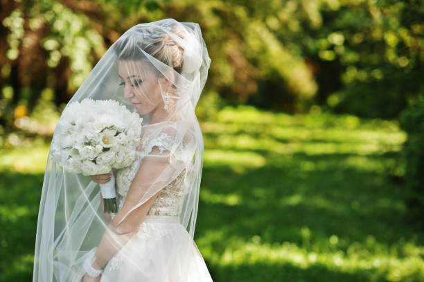 istock Awesome gorgeous blonde bride under veil with wedding bouquet at hands. 662903122
