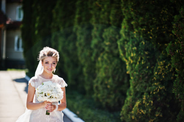 istock Awesome gorgeous blonde bride with wedding bouquet at hands at sunny day. 662904488
