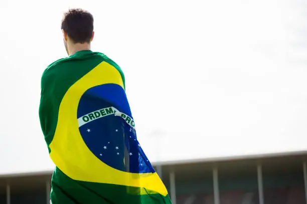 Athlete with brazilian flag wrapped around his body in stadium