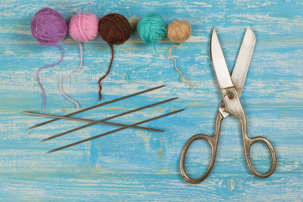 istock Scissors, knitting needles and colored threads on a blue wooden table. 662925748