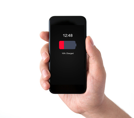 Isolated male hand holding black phone with low charged battery on screen