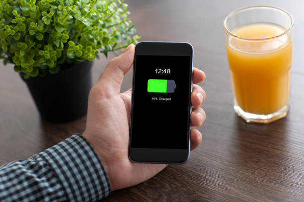istock man hand holding phone with charged battery screen in office 662936718