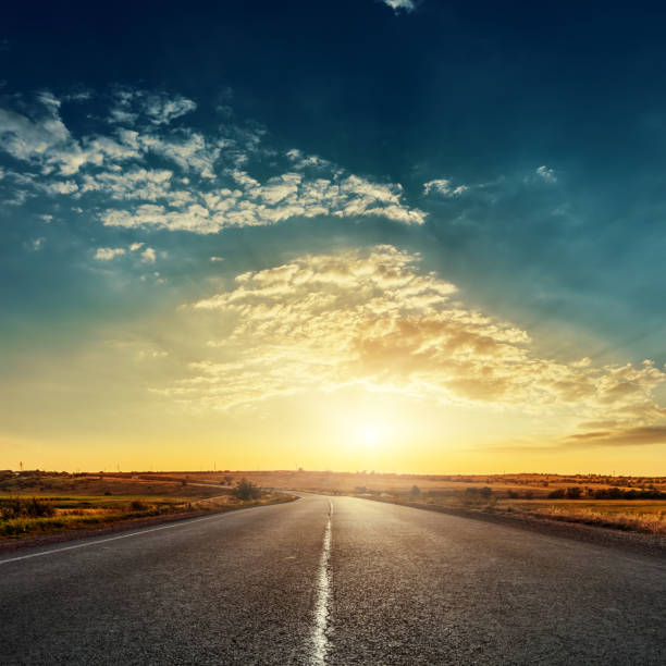 low sun in dramatic sky over asphalt road - freedom sunset landscape travel imagens e fotografias de stock