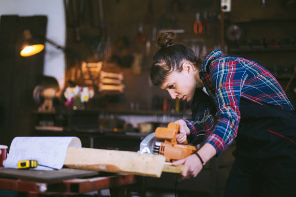 istock Concentrated Carpenter Girl Cutting Plank With Circular Saw 662984788