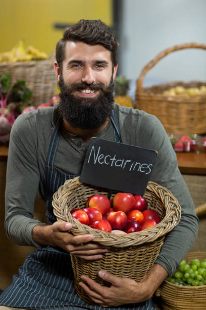 istock Smiling vendor holding a basket of nectarines 663005698