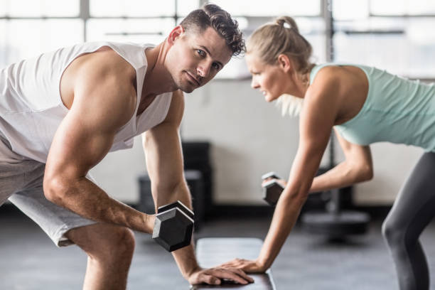 istock Couple exercising with dumbbells in gym 663006604