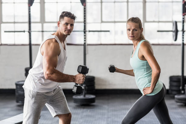 istock Couple exercising with dumbbells in gym 663012462