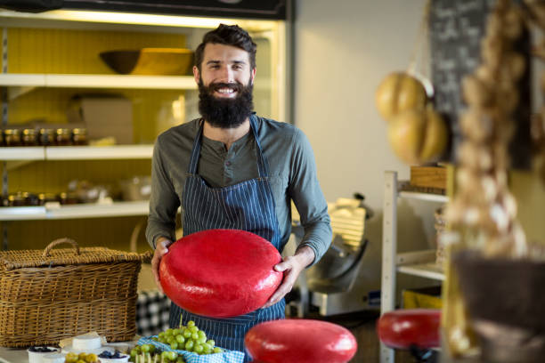 istock Smiling salesman holding a gouda cheese 663012468
