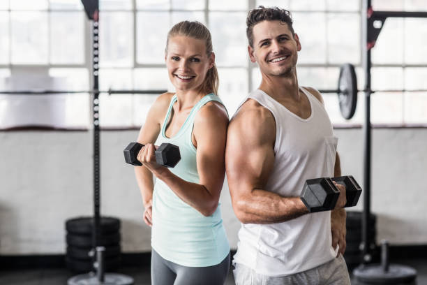 istock Back to back couple exercising with dumbbells 663014730