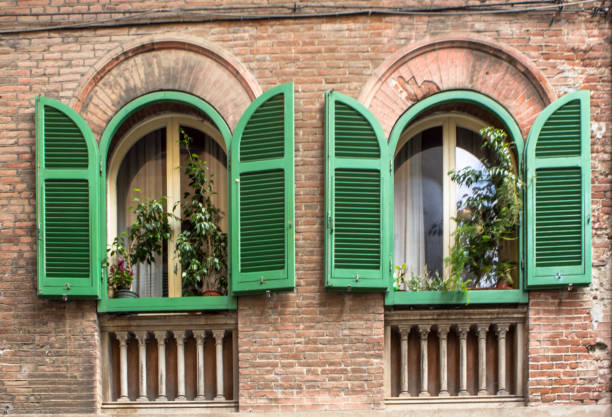 Old, brick house with opened green shutters in Pisa, Tuscany, Italy