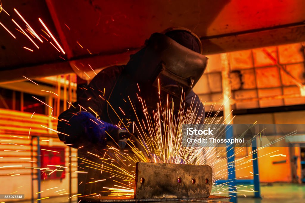 Worker is welding steel part in car factory Car Plant Stock Photo