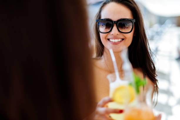 istock Beautiful young women drinking cocktails on beach 663118376