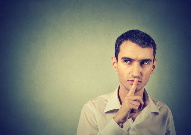 istock young suspicious man giving Shhhh quiet, silence, secret gesture 663126734