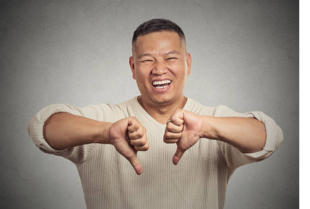 sarcastic young man showing two thumbs down sign hand gesture Closeup portrait sarcastic young man showing two thumbs down sign hand gesture, happy that someone made mistake lost failed isolated grey wall background. Negative emotion facial expression feeling situational irony stock pictures, royalty-free photos & images