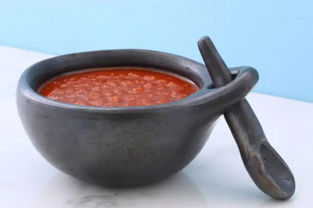 Artisan mexican red hot sauce on retro vintage carrara marble in beautiful terracotta pot, perfect for all your Mexican, tex-mex recipes and sides.