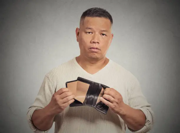 Photo of stressed, upset, sad, unhappy middle aged  man standing with, holding empty wallet