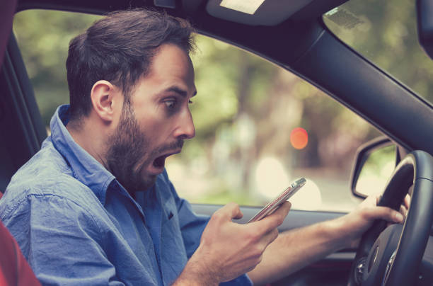 istock Man sitting inside car with mobile phone in hand 663161564