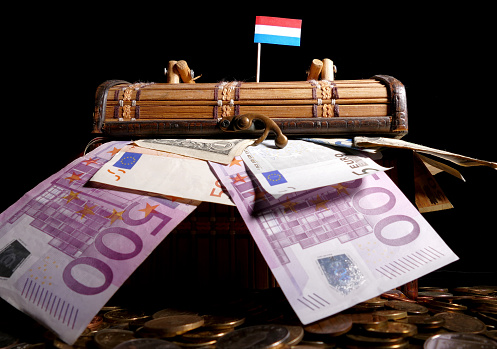 Luxembourg flag on top of crate full of money