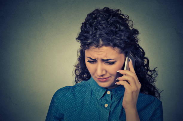 istock unhappy young woman talking on mobile phone looking down 663181132