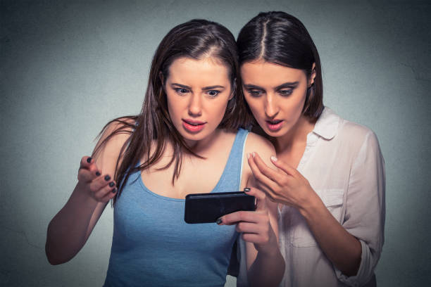 istock Two surprised girls looking at cell phone 663190626