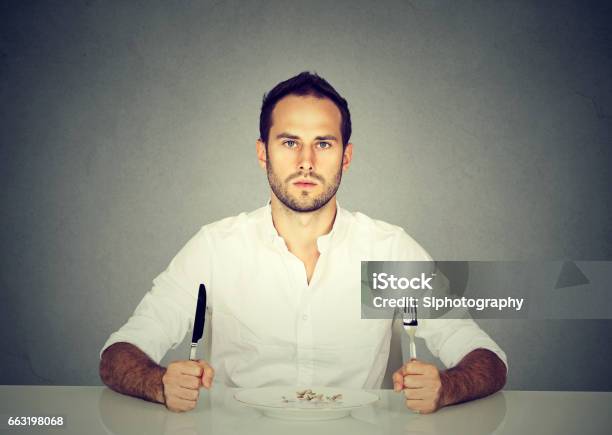 Photo libre de droit de Homme Avec Fourchette Et Couteau Assis À Table Avec Le Plat Vide banque d'images et plus d'images libres de droit de Hommes