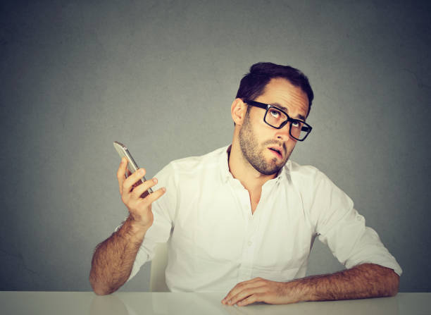Closeup annoyed young man with cellphone Closeup annoyed young man with cellphone. Long wait times, horrible conversations concept. Human emotion face expression reaction gloomy mood stock pictures, royalty-free photos & images