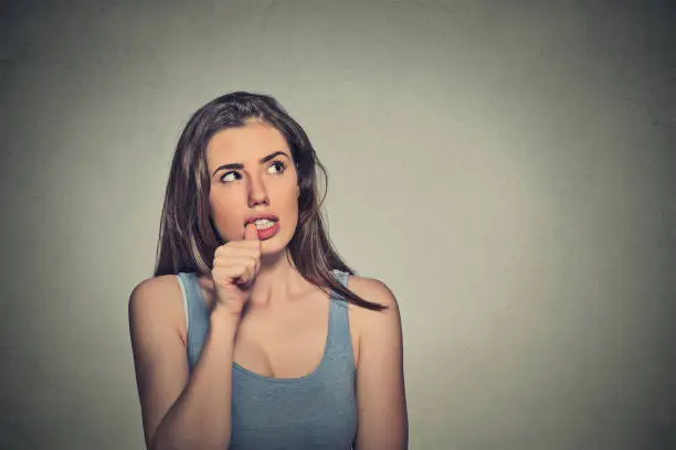 Photo of nervous looking young woman biting her fingernails