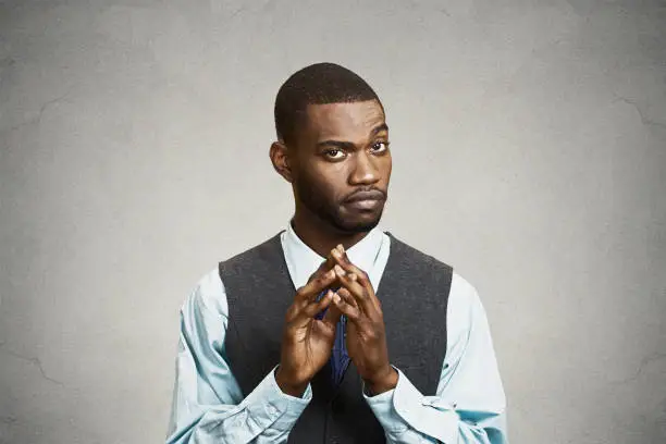 Closeup portrait, sneaky, sly, scheming young business man, worker trying to plot something, screw someone, isolated black background. Negative human emotions, facial expressions, feelings, attitude