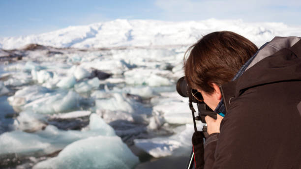 istock Young man (photographer) shooting the icebergs with a reflex camera 663283156