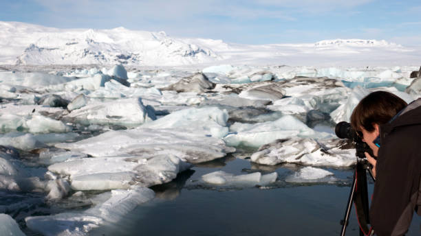 istock Young man (photographer) shooting the icebergs with a reflex camera 663283910