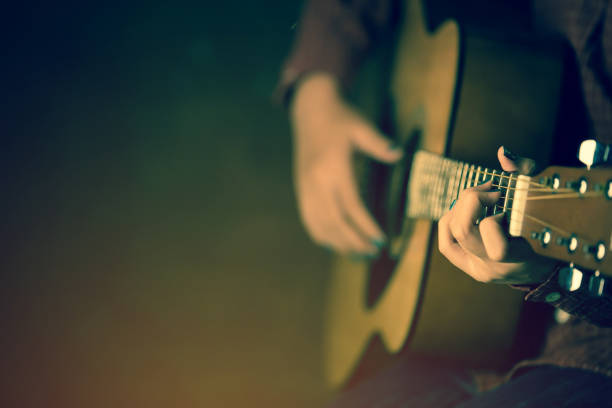 women playing acoustic guitar close-up